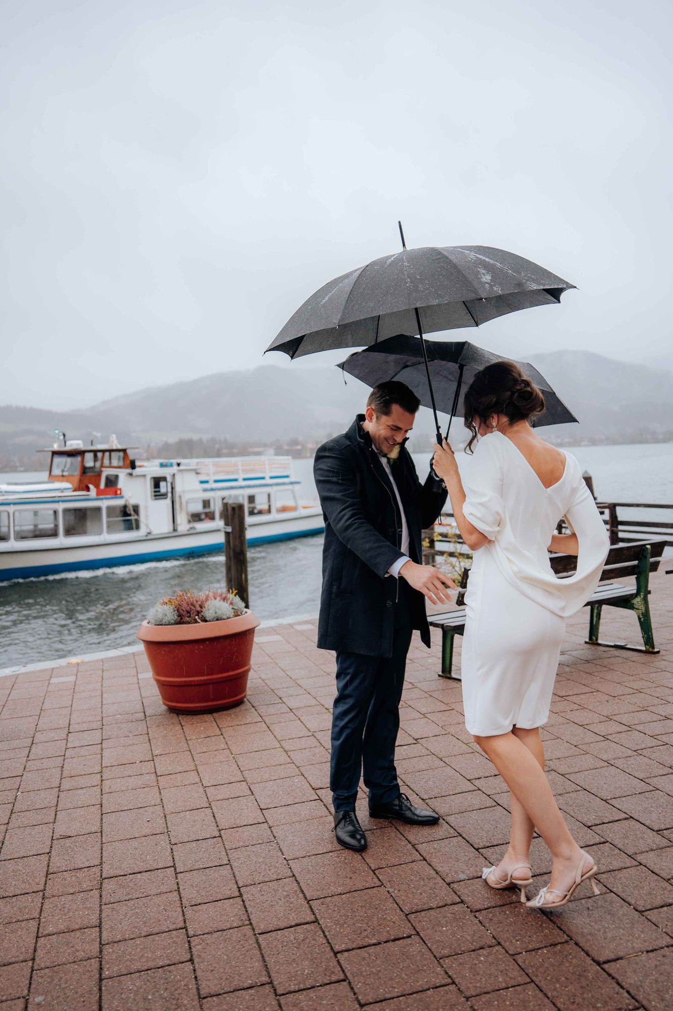 Brautpaar mit Regenschirmen an der Seepromenade am Tegernsee