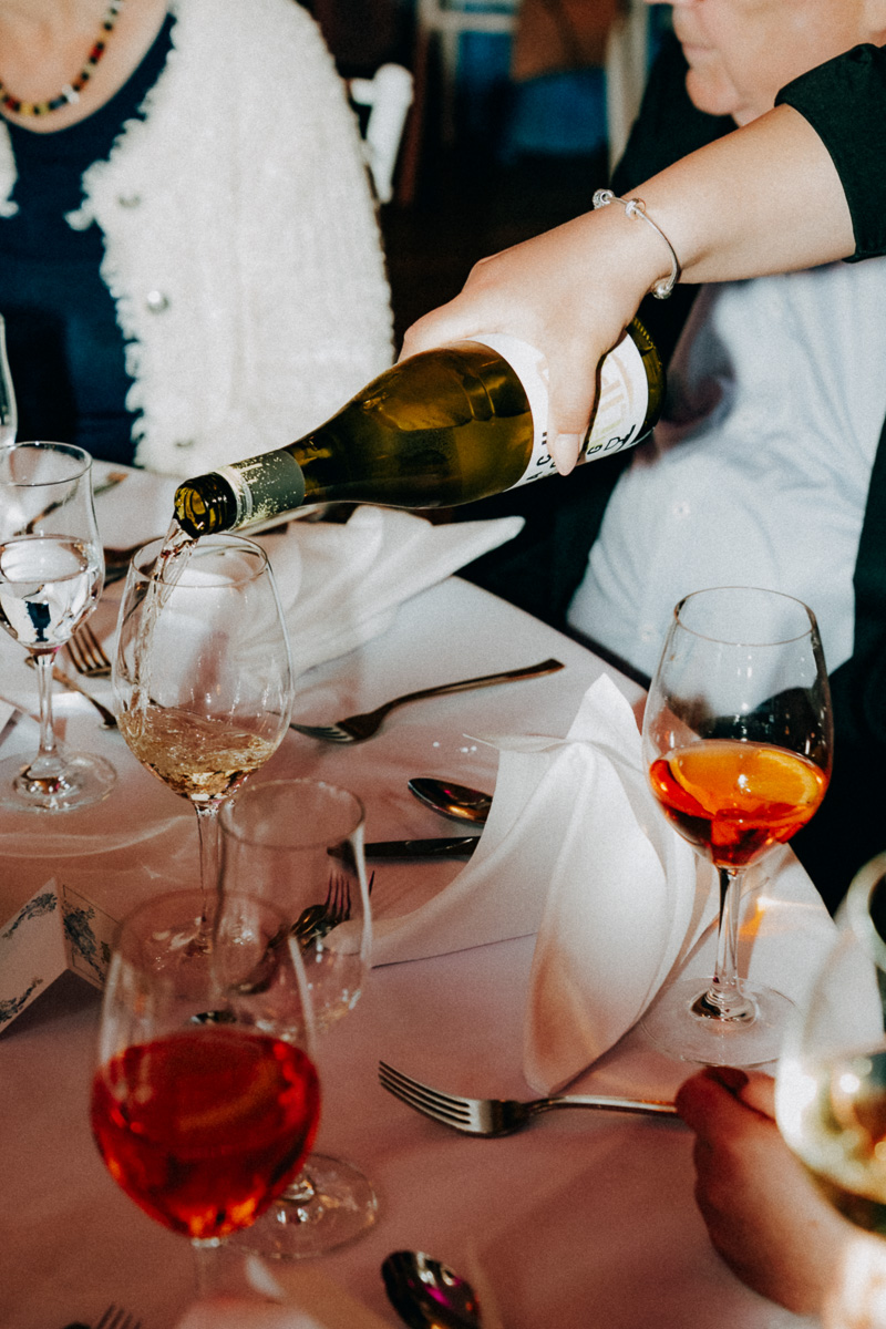 Eine Kellnerin schenkt auf einer Hochzeit Wein ein, Blitzfoto im 90s Look
